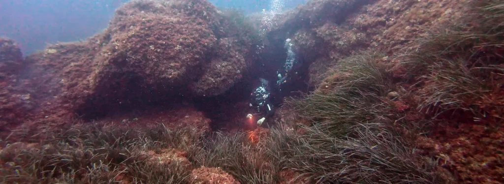 Eneritz from Diving Menorca exiting a little cave at Illa Porros in Menorca, Spain