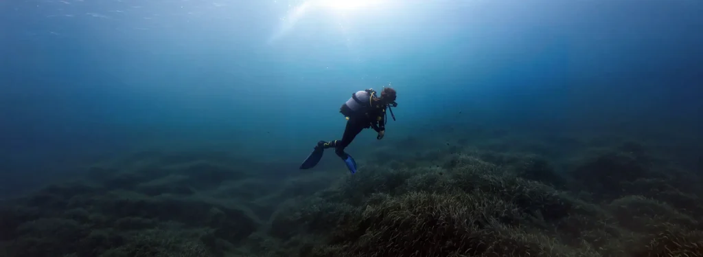 Paula over a field of Posidonia looking into the blue at Arenal d'en Castell, Menorca, Spain