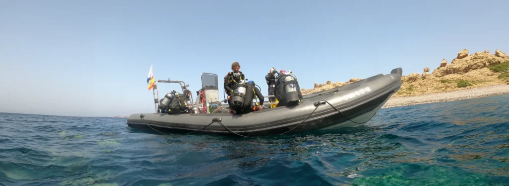 A group of divers waiting to enter the water in Fornells, Menorca, Spain